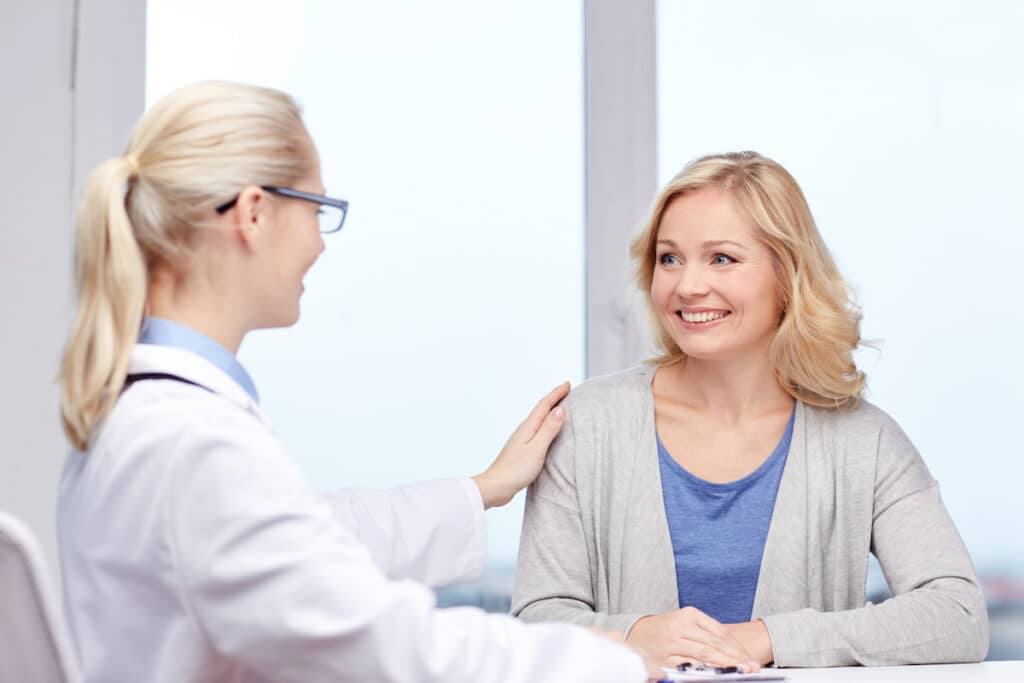 A women's health doctor meeting with a patient and patting her shoulder.