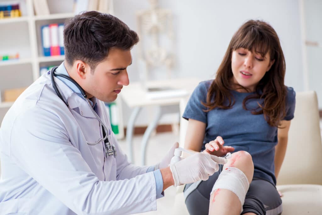 Patient visiting a doctor in a wound care clinic after sustaining a sports injury on her knee.