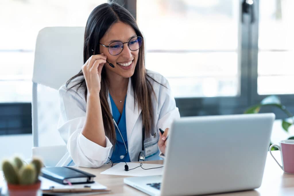 A doctor getting on a telehealth call with a patient. She is wearing a headset with a microphone.