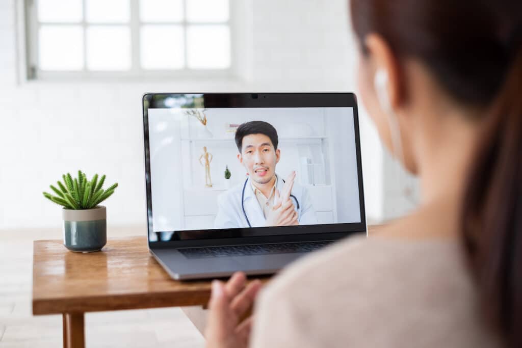 A woman wearing earbuds has a virtual consultation with a doctor in cardiology at Healthy Connections.