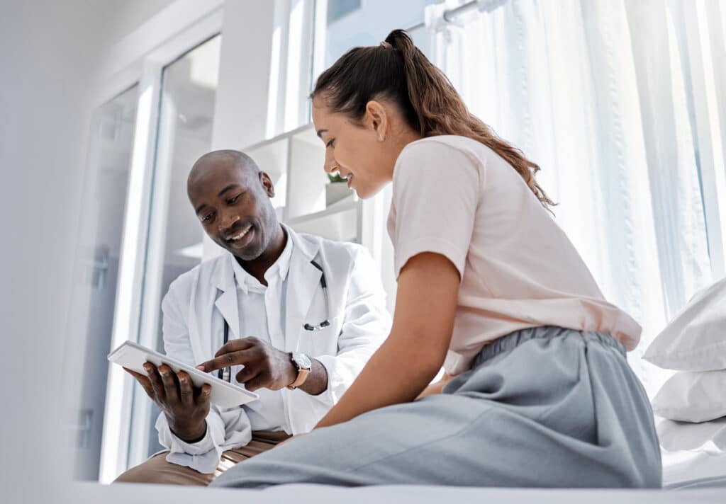 A doctor talking to a patient and showing her something on a tablet after her women's health appointment.