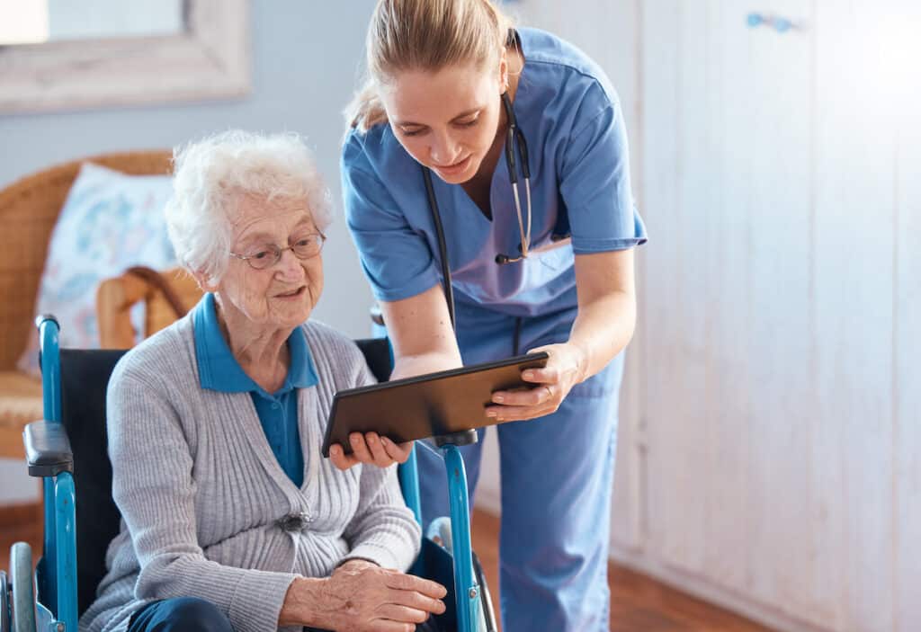 An elderly woman talks to her nurse about primary care.