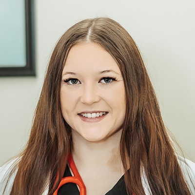 Brandi Webb, APRN, professional headshot in her scrubs and lab coat.